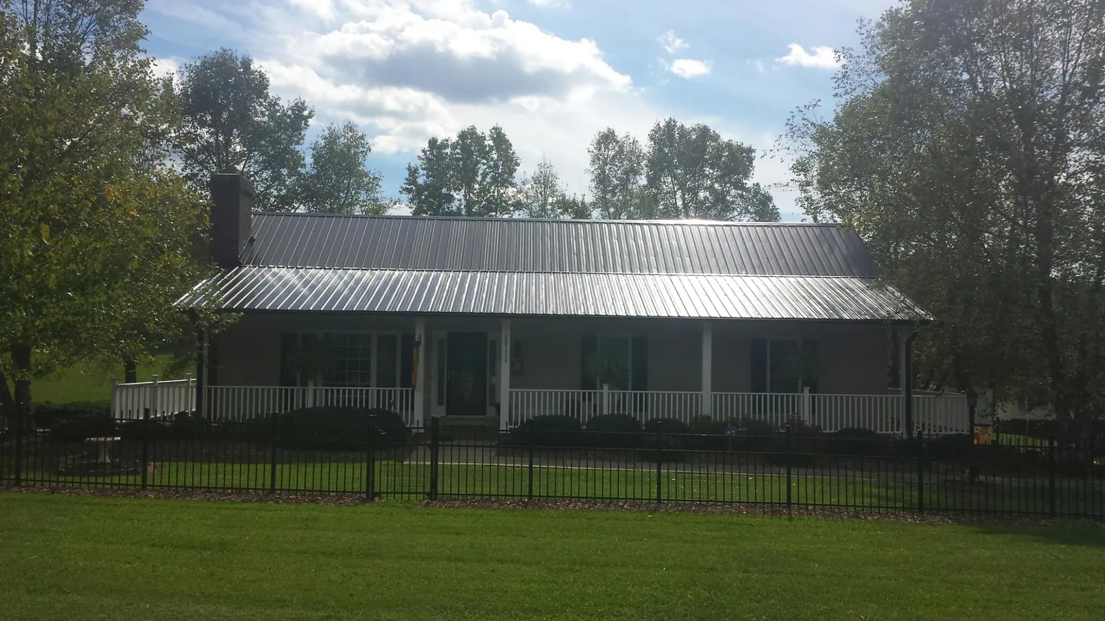 Gray metal roof on a brick ranch with a full width front porch — Gutter Guard Installation work by our crew in Conklin