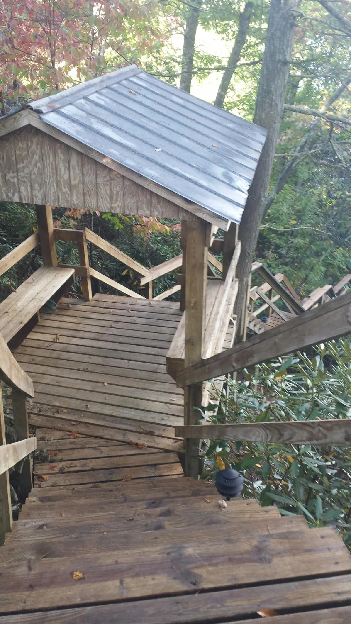 Metal roofed shelter over wooden steps on a wooded walkway — Skylight Repair & Installation work by our crew in Conklin