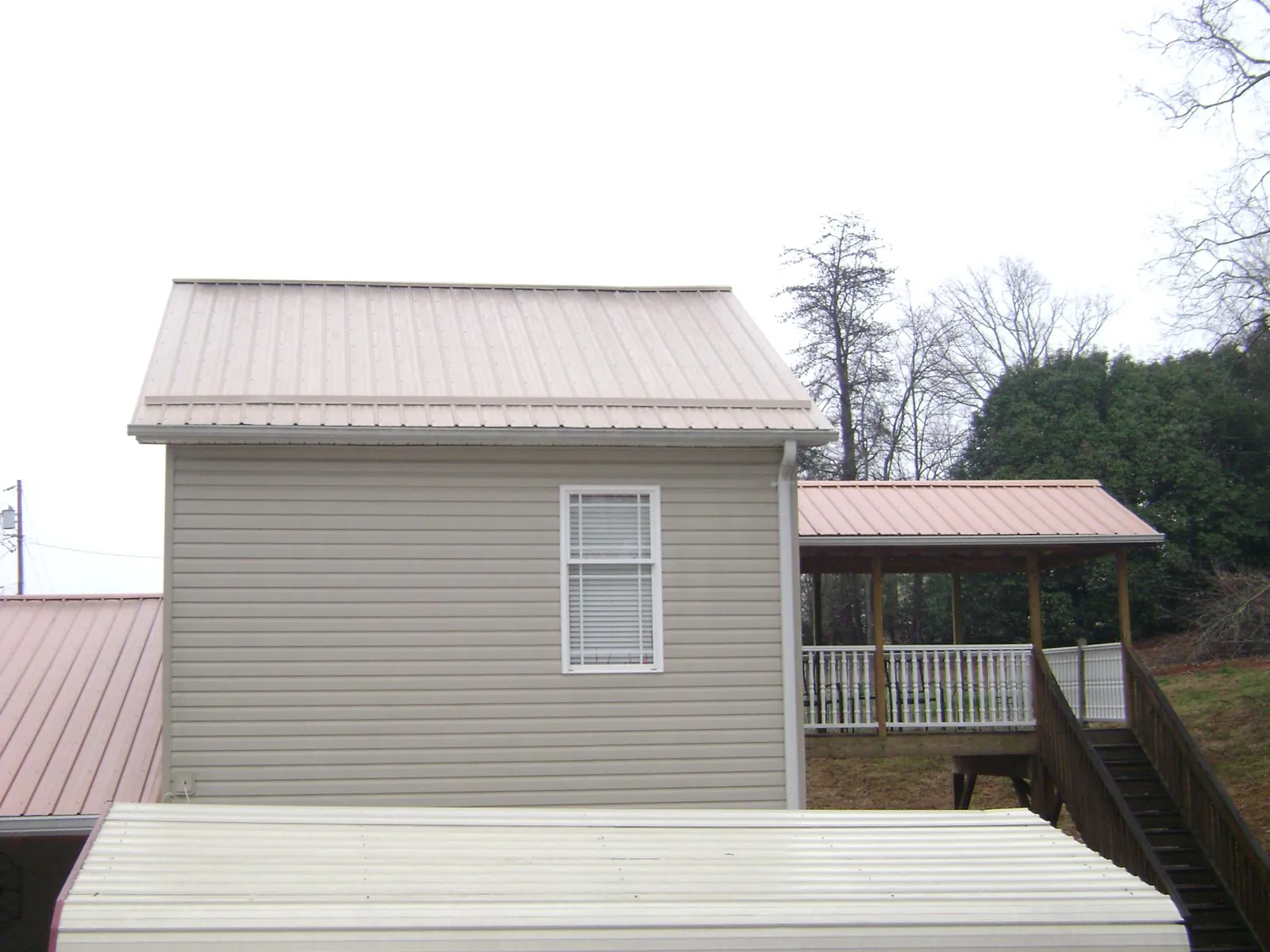 Tan metal roofs on a two story addition and attached porch, from a Roof Replacement job in Conklin