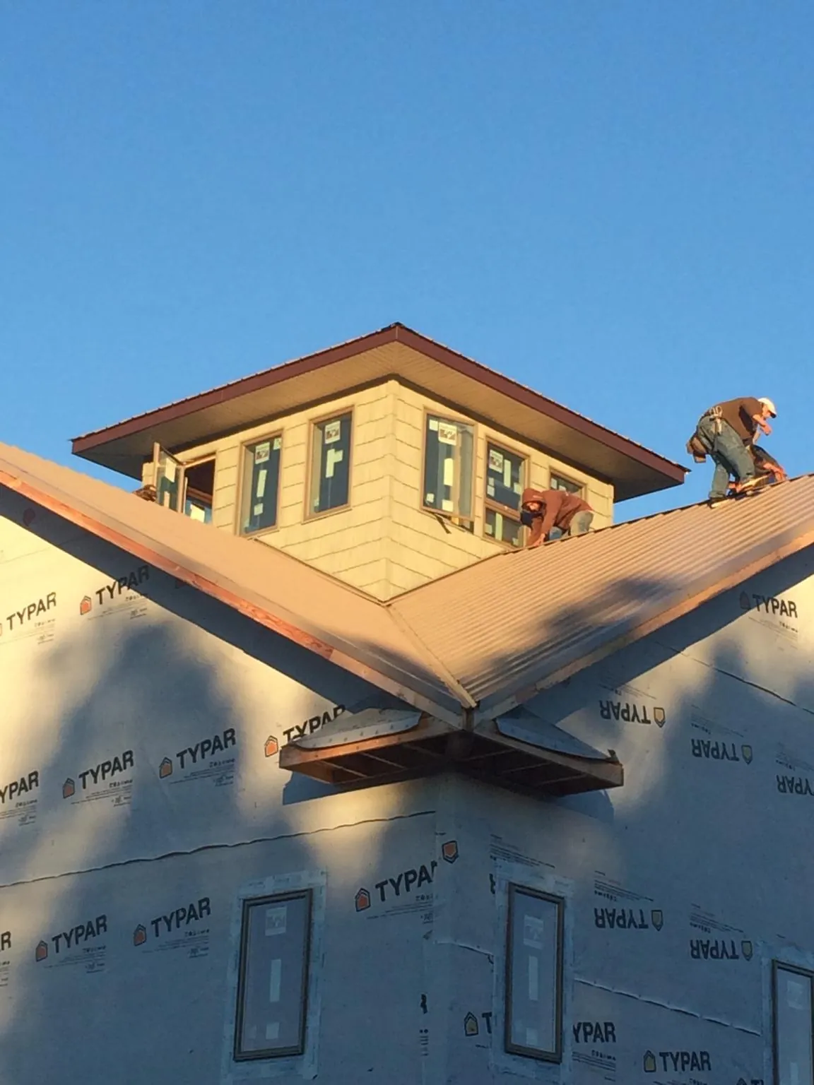 Roofers working around a rooftop cupola on a new metal roof at sunset — Roof Waterproofing in Conklin by Roofing Brothers